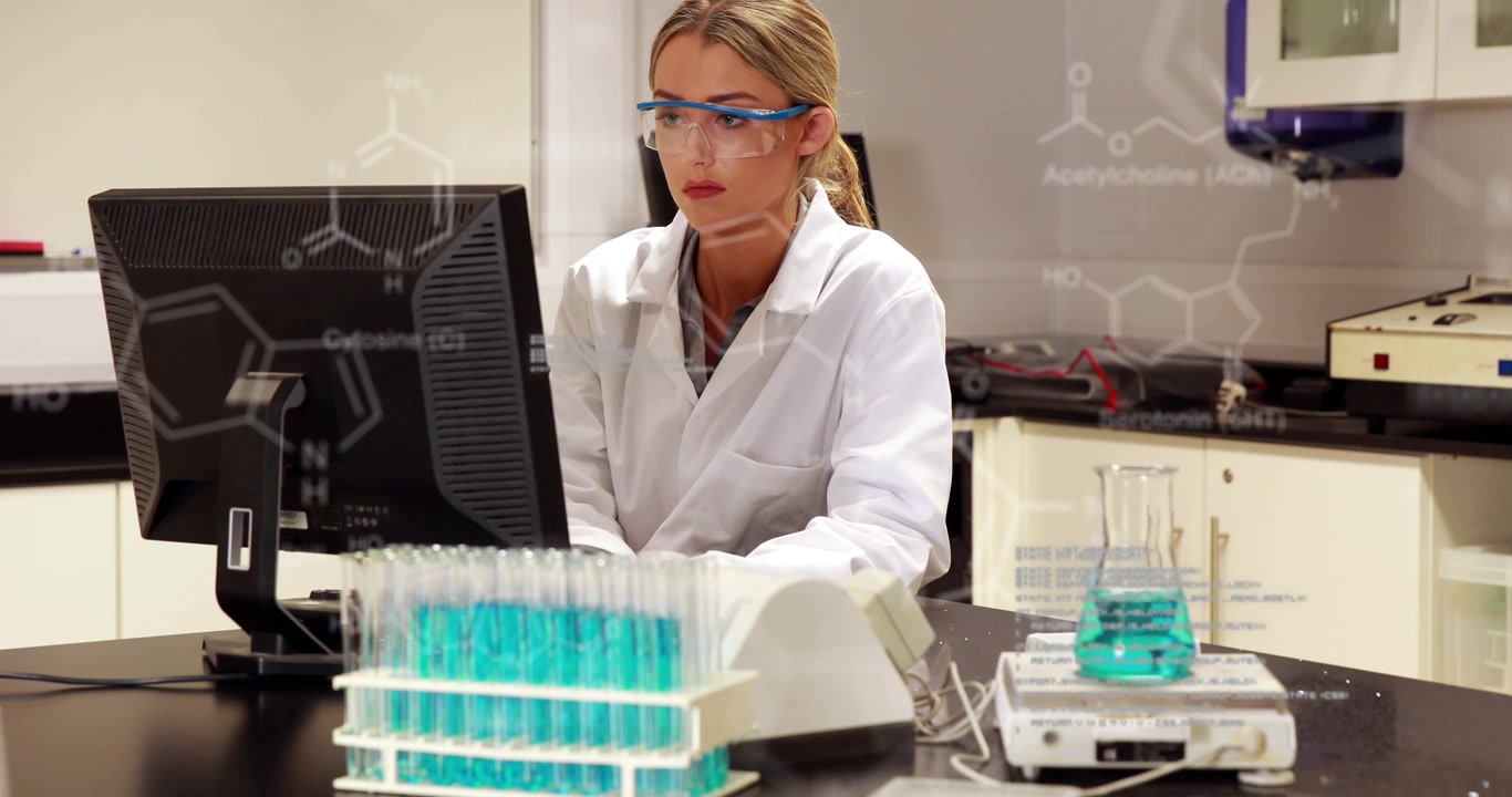 Kvindelig videnskabsmand arbejder på computer i laboratorium med digitale kemiske formler