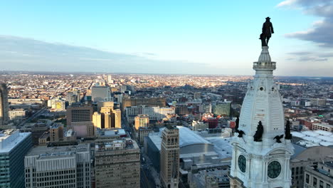 Cinematic-shot-of-City-Hall-clock-tower-and-William-Penn-statue-overlooking-Philly-skyline