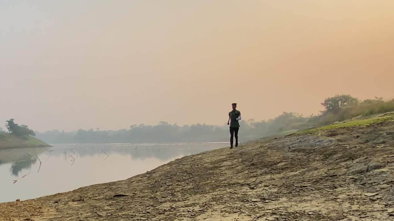 hombre corriendo hacia la cámara, corredor corriendo por el río en sylhet, cámara lenta