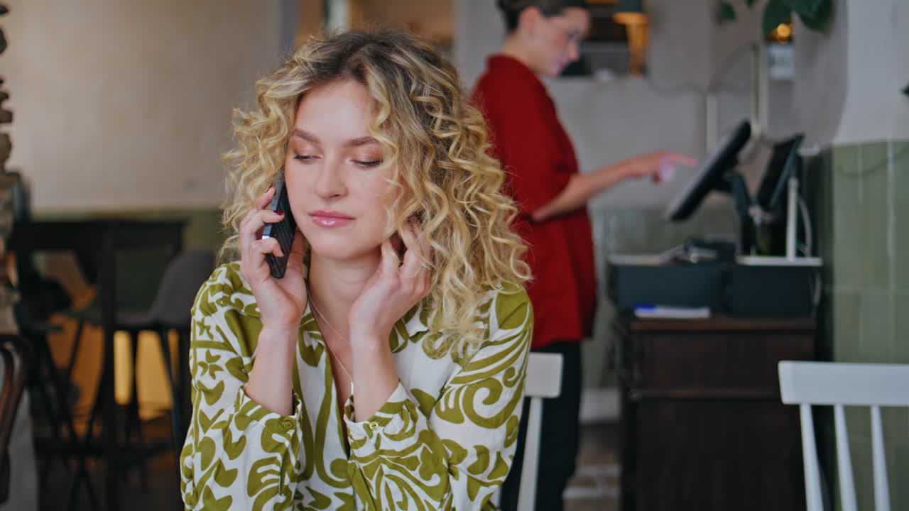 Relaxed blonde calling mobile phone waiting order in small restaurant closeup