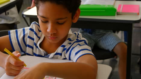 Mixed-race-schoolboy-studying-at-desk-in-classroom-at-school-4k