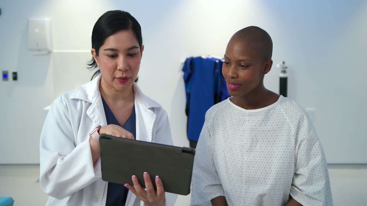 Female doctor holding tablet and explaining results in exam room, engaging African American patient