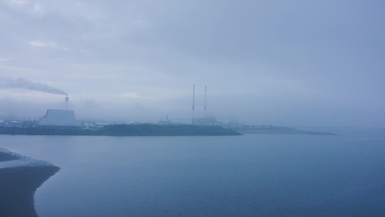 안개가 가득한 더블린의 황혼: 샌디마운트 해변, 풀베그 타워, 폐기물에서 에너지 발전소, 해안선을 따라 혼자 산책하는 사람