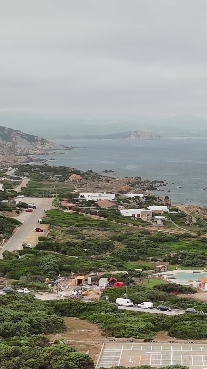Vista costiera della Sardegna con case e mare sotto un cielo nuvoloso