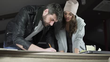 Young-man-and-woman-working-on-a-project,-drawing-and-thinking-in-modern-office.-Cheerful-colleagues.-Coffee-cup-and-laptop-on