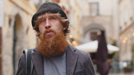 Sad unhappy frustrated young man walking alone in city street feeling bad annoyed grief problem