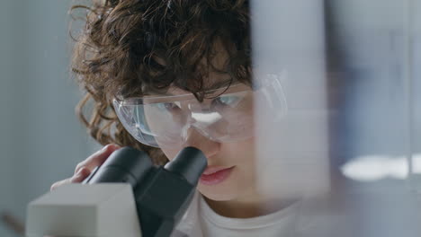 close-up of female scientist analyzing specimen under microscope