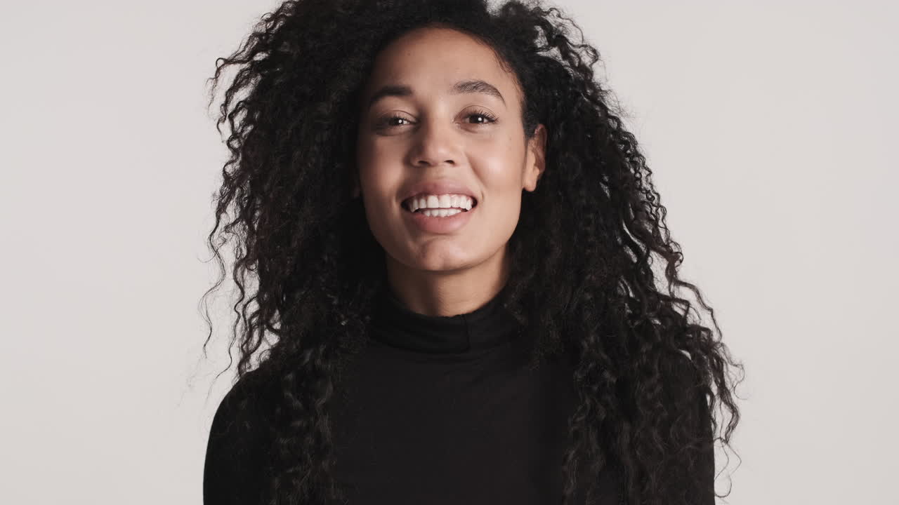 una mujer afroamericana sonriendo sobre un fondo blanco.