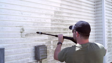 homeowner cleaning vinyl siding with a pressure washer