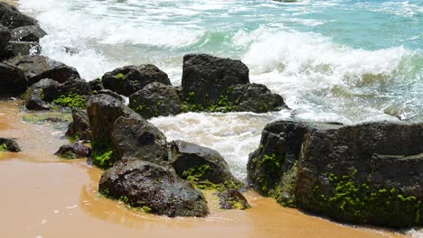 las olas del océano golpean la orilla rocosa en la playa