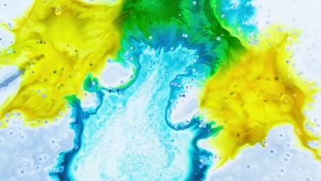 yellow and green ink spreading organically in water with a central white space