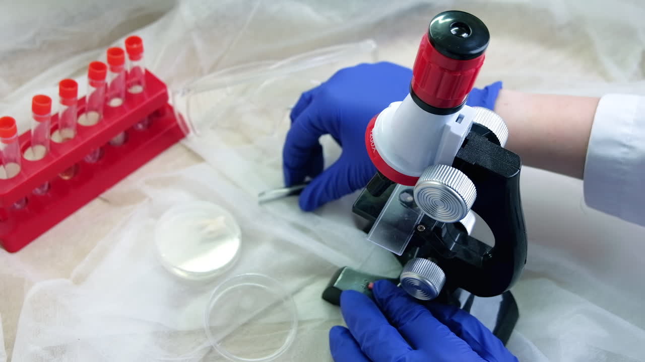 Uomo con i guanti che lavora con un microscopio, provette, bicchieri