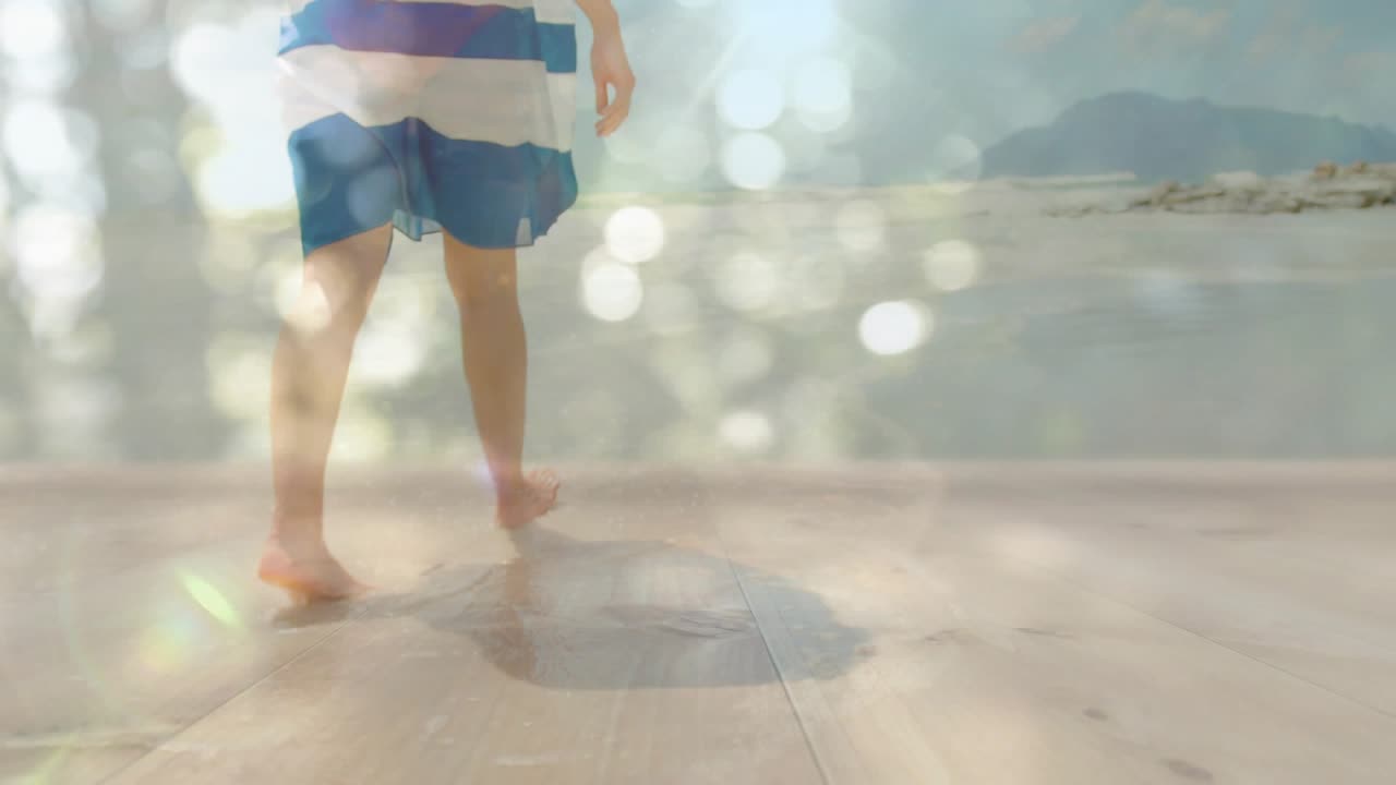 Vertikales Video: Barfuß gehender Mann auf Deck, Ufer im Hintergrund, weicht feuchter Stelle unter Bokeh-Effekt aus, zum Thema Reisen.