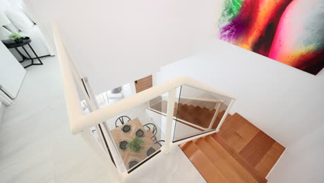 Modern-staircase-overlooking-dining-table-with-chandelier-and-colourful-modern-artwork