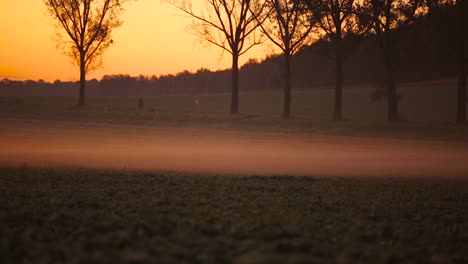 the beautiful country road by the misty, magical countryside of poland with orange sky in the background - wide shot