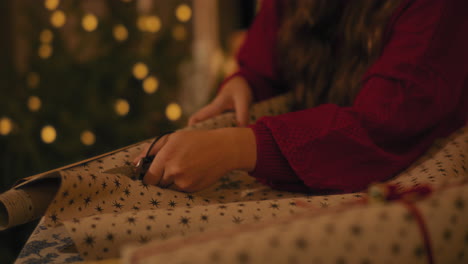 mujer cortando papel mientras envuelve regalos