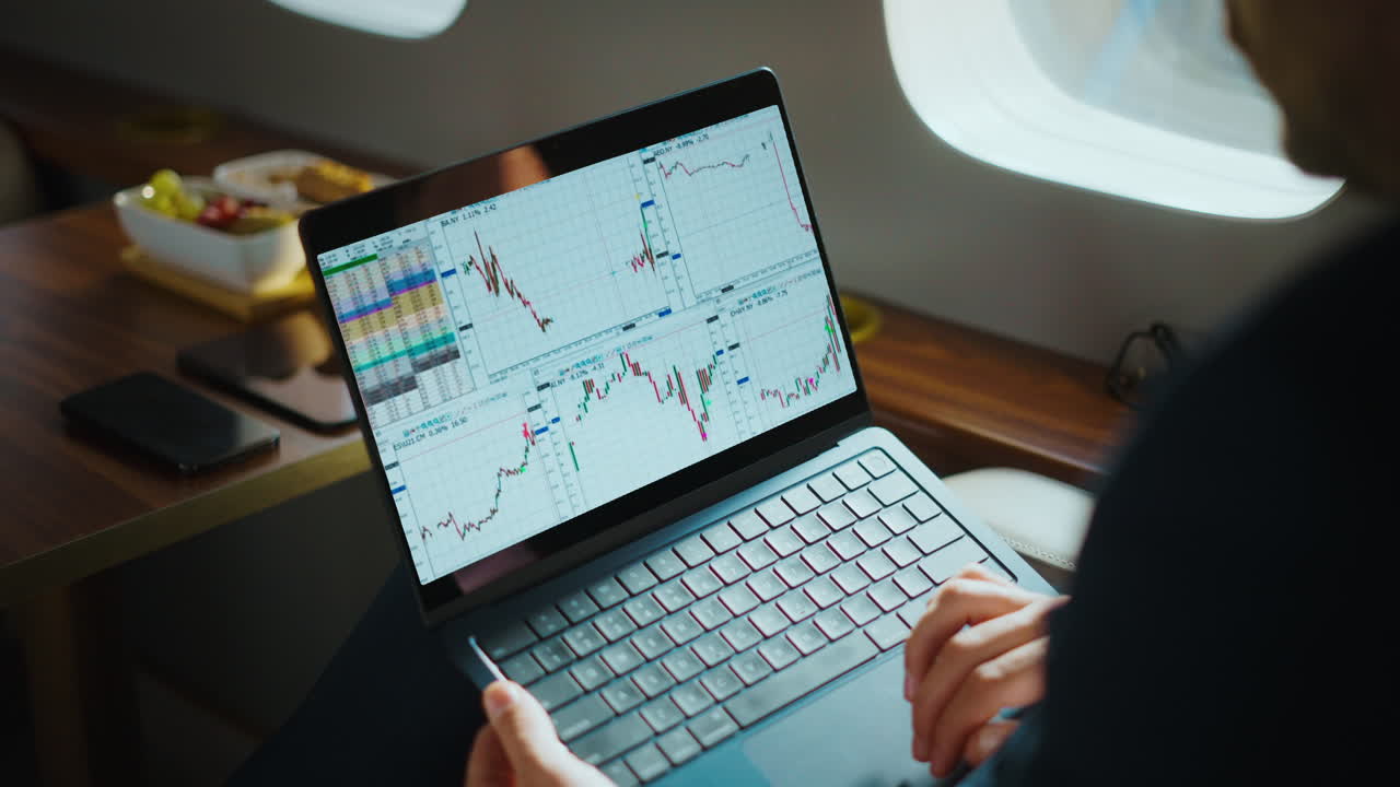 Businessman analyzing stock market data on a laptop in a private jet
