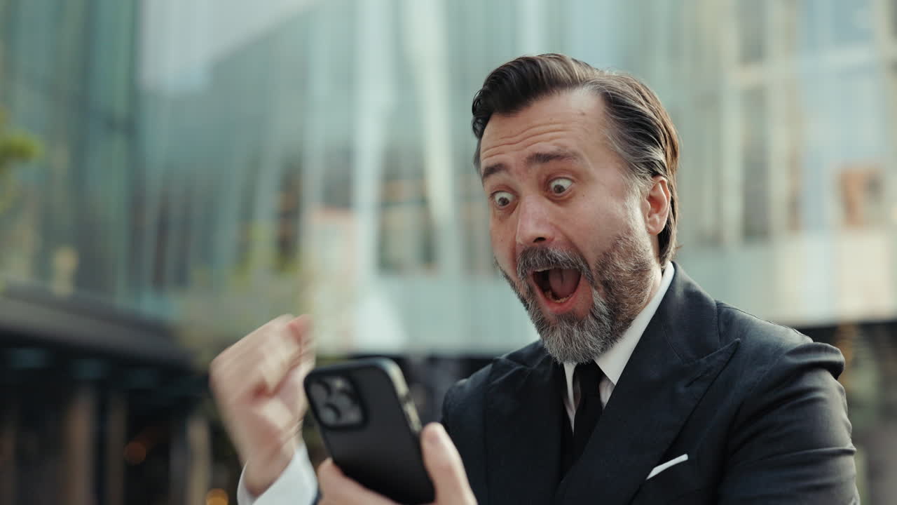 Uomo d'affari entusiasta reagisce a una buona notizia sullo smartphone