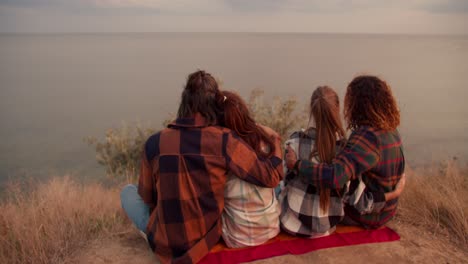 shooting from behind: two couples in love are resting on the seashore. two couples in checkered shirts are hugging. rest in the country house by the sea