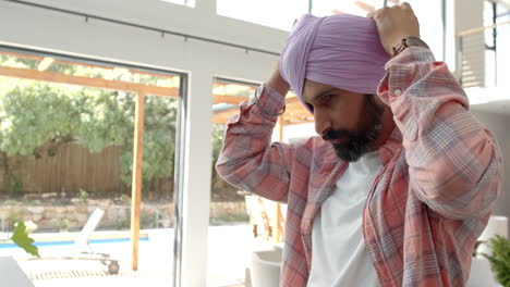 adjusting turban, man standing indoors in casual attire near window
