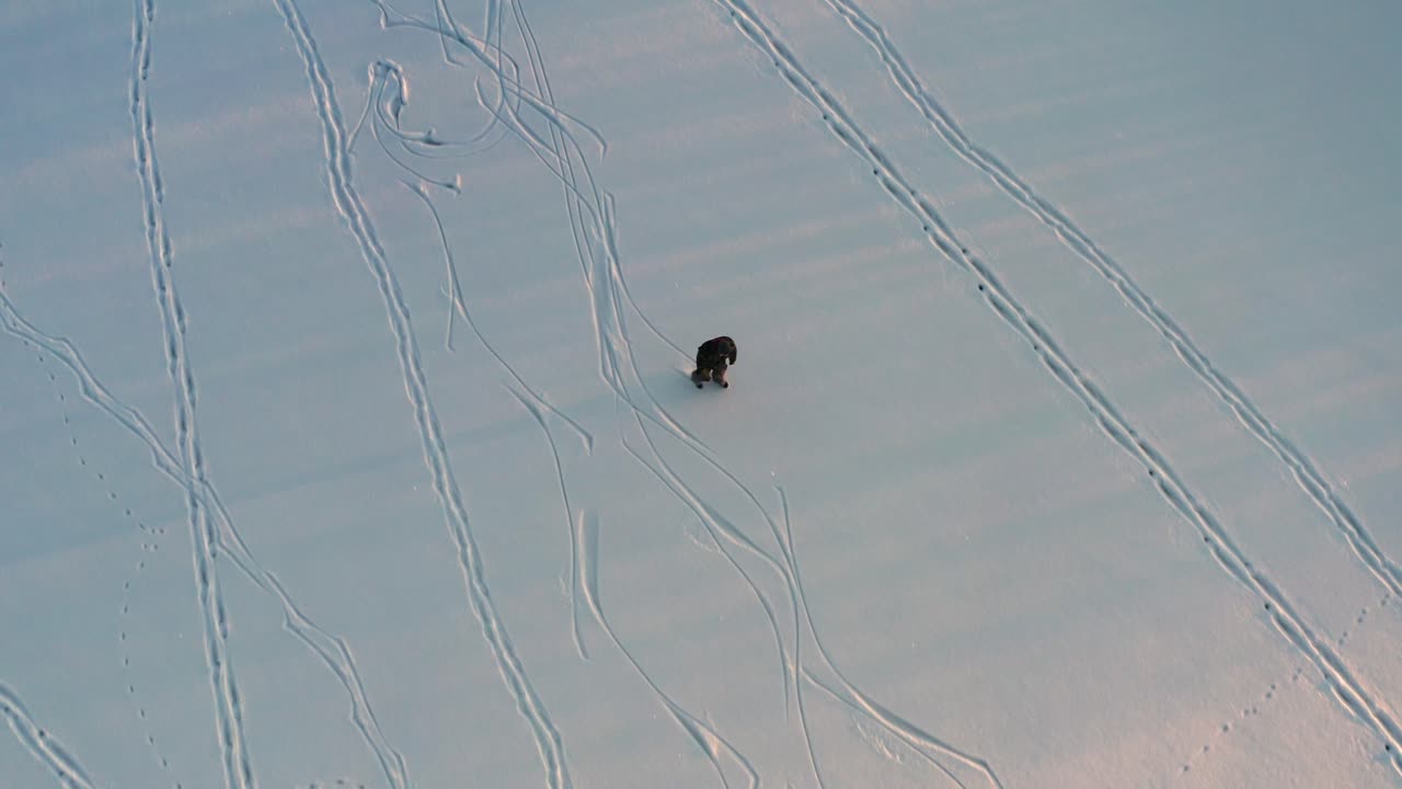 겨울 해가 지는 동안 얼어붙은 호수에서 아이스 스케이트를 타는 사람의 영화적인 공중 사진
