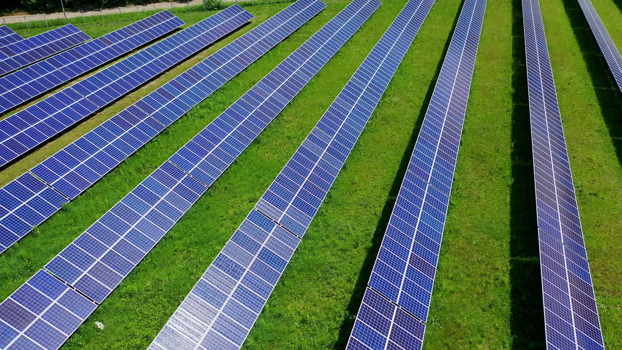 Large solar farm on field. Rows of blue sunny batteries receive clean ecological energy at sunlight. Renewable energy on solar power station. Aerial view