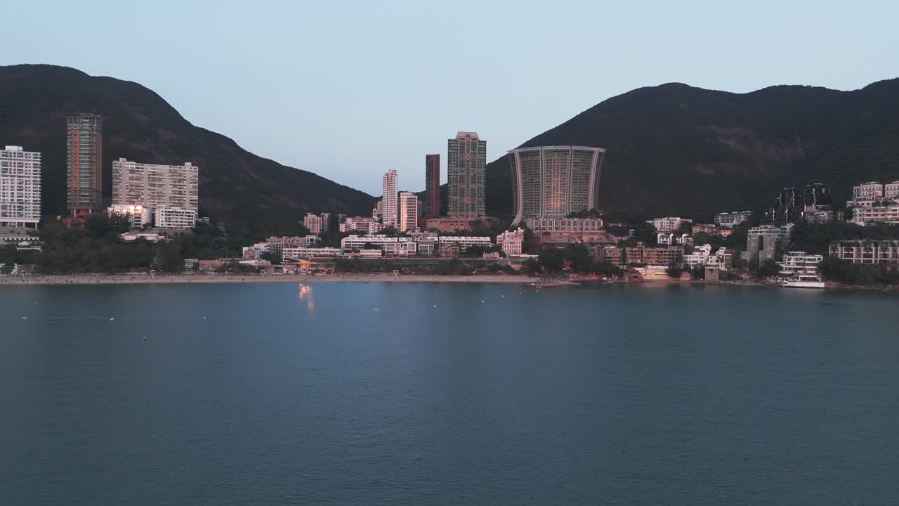 Droneoptagelse fra luften af Repulse Bay, Hong Kong, der viser sandstrand, turkisblåt vand og højhusbygninger langs kysten med panoramaudsigt over byens skyline
