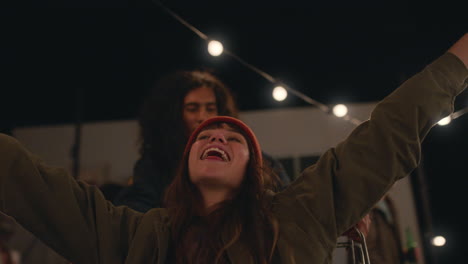 Hermosa-Joven-Divirtiéndose-Sentada-En-Un-Carrito-De-Compras,-Grupo-De-Amigos-Disfrutando-De-Una-Loca-Fiesta-En-La-Azotea-Por-La-Noche-Celebrando-Juguetonamente-El-Fin-De-Semana