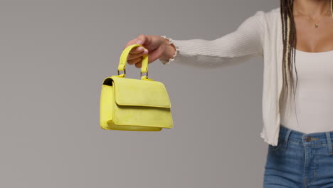 close up of female social media influencer producing user generated content holding out yellow fashion handbag