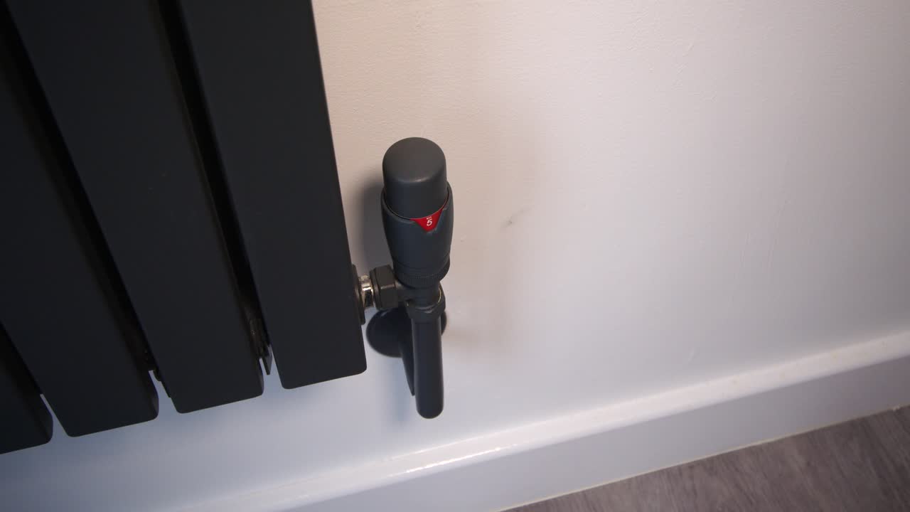 female model turning up a anthracite radiator thermostat from 5 to 3
