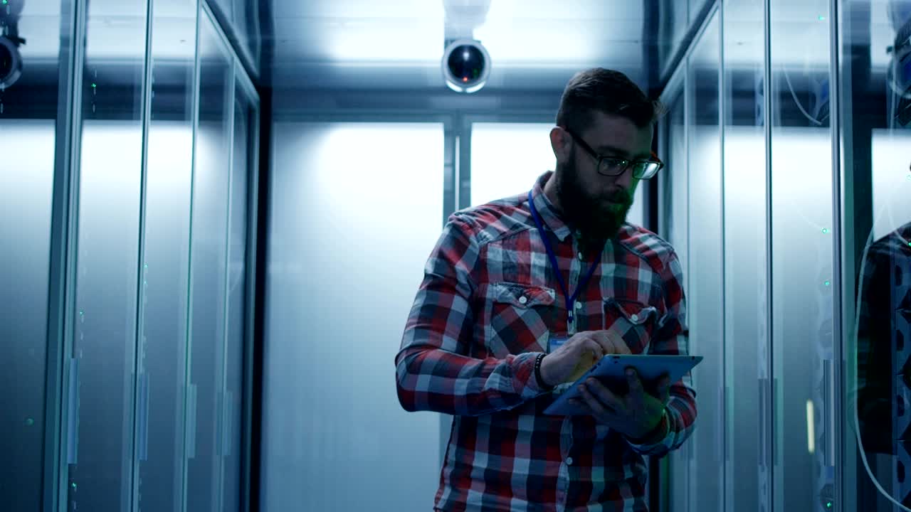 Bearded man with tablet checking server computer