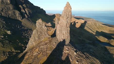 ancient volcanic plug stone spire the old man of storr bathed in early morning winter sunshine with reveal of lowlands and coastline