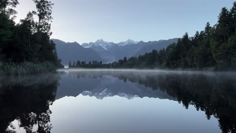 Ruhiger-Sonnenaufgang-Am-Lake-Matheson-Mit-Perfekter-Spiegelung-Der-Schneebedeckten-Berggipfel