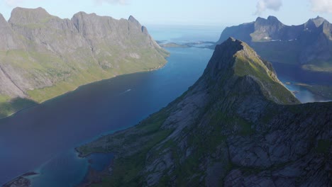 Drone-shot-of-Lofoten-steep-cliffs-and-mountains-rising-from-deep-blue-sea