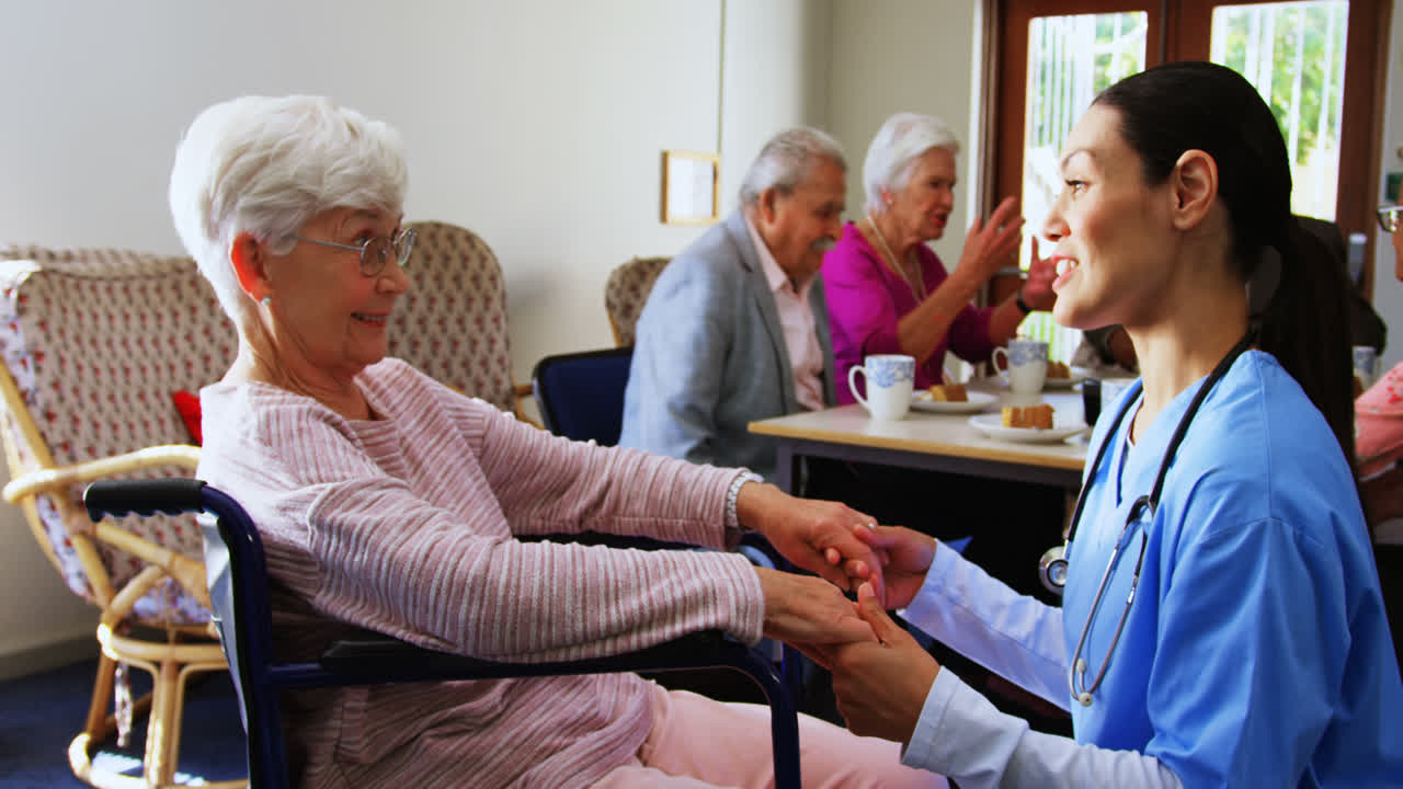 Side view of Caucasian female doctor consoling sad disabled senior woman at nursing home 4k