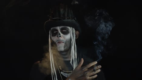 creepy man with skeleton makeup in top-hat. guy smoking cigar, making faces, looking at camera