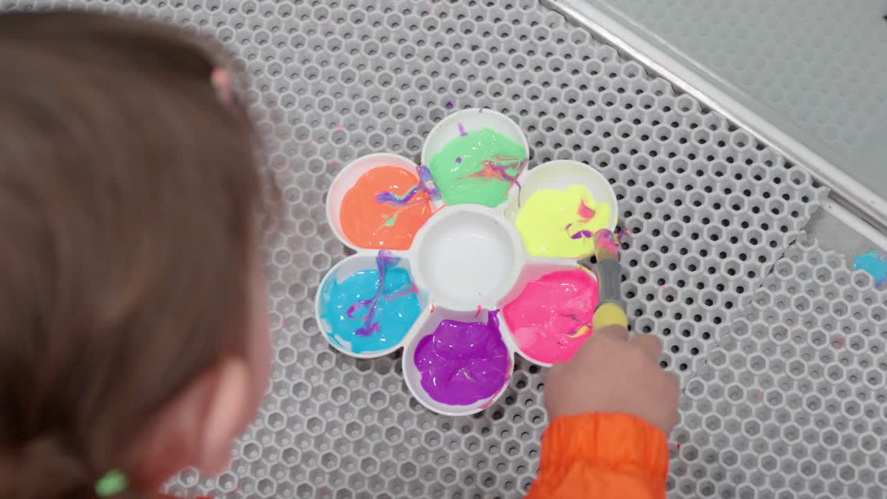 niño pequeño con pincel y paleta mezclando colores