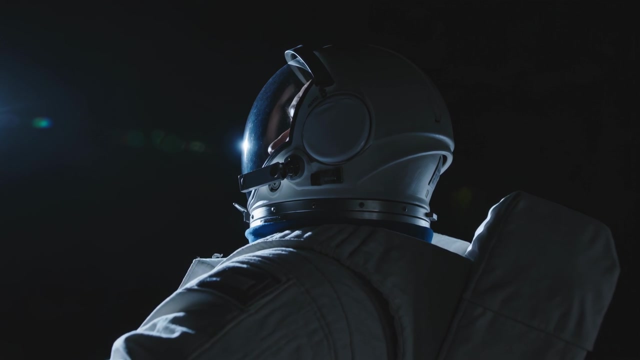 Astronauta con traje espacial girando e inclinando el casco a la izquierda en el vacío, con un haz creciendo, provocando un destello en la visera, PLSS.