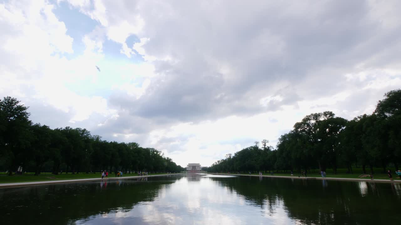 전경에 있는 사람들과 함께 반사 연못에서 찍은 링컨 기념관 앞 계단까지 물 쪽으로 천천히 기울어집니다.