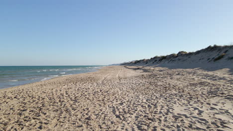 aerial view with slow upward movement of empty beach with dunes in the mareny, valencia, spain