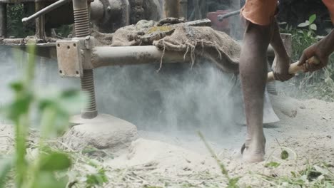 Indian-workman-digs-gravel-out-of-the-way-while-Bore-well-drilling-machine-digs-through-soft-stone-slow-motion