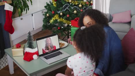 African-american-mother-and-daughter-having-a-videocall-on-laptop-at-home-during-christmas