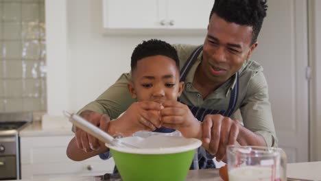 Padre-Afroamericano-Enseñando-A-Su-Hijo-A-Romper-Huevos-Mientras-Hornea-En-La-Cocina-De-Casa