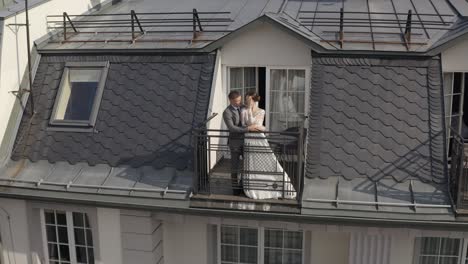 Caucasian-newlyweds-bride-embracing-groom-on-balcony-in-hotel-room,-aerial-view