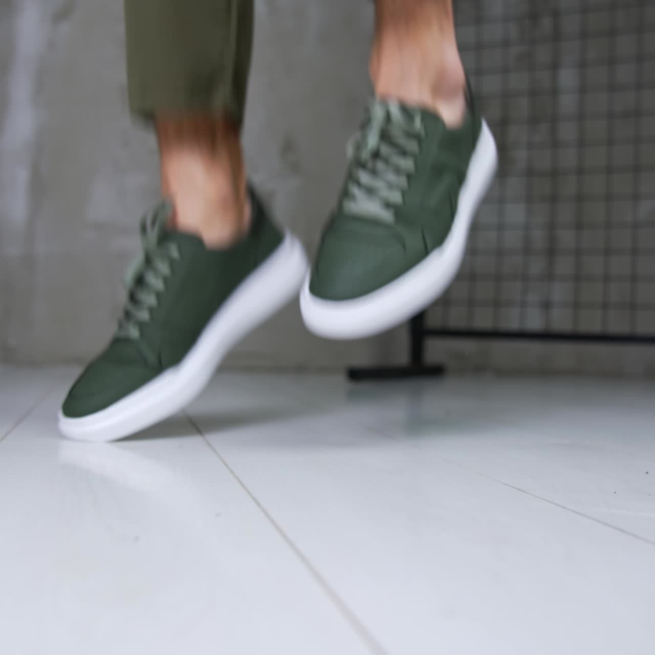Man in khaki jeans and sneakers jumps demonstrating comfortable sport shoes. Close up. Fashionable stylish footwear presentation in studio