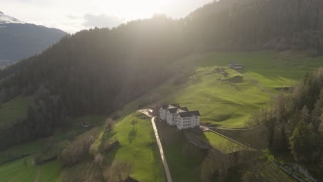 aerial of an old building in a swiss mountain valley in summer at sunset