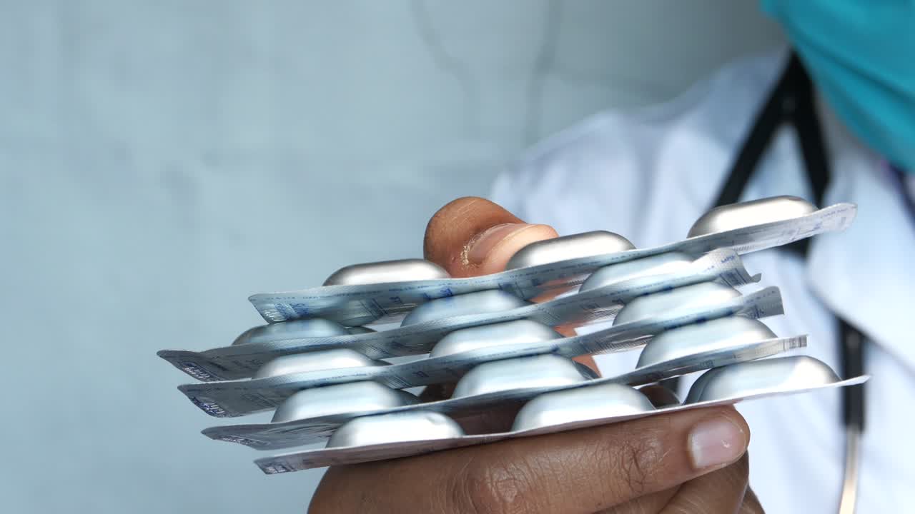 Medico che tiene confezioni blister impilate di farmaci