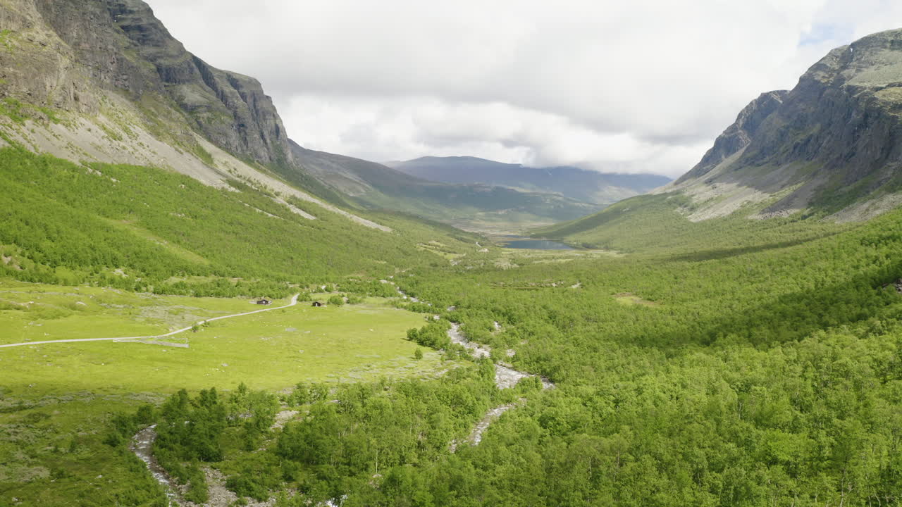 Fantastisk landskap av et fjellpass med frodig grønn eng og bekk på dagtid i Hydalen, Hemsedal, Norge.