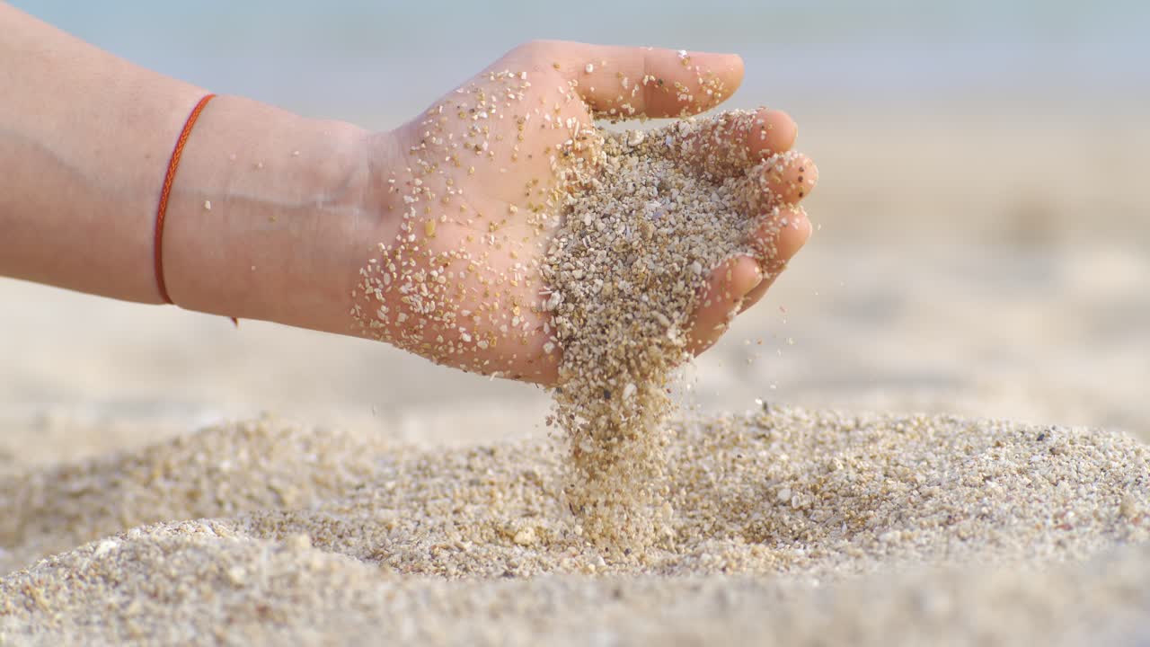 Sand falling from hand in slow motion on a beach. Vacation and travel concept. Shot on super slow motion camera 1000 fps.