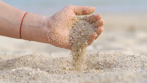 arena cayendo de la mano en cámara lenta en una playa. vacaciones y concepto de viaje. disparado en cámara súper cámara lenta 1000 fps.